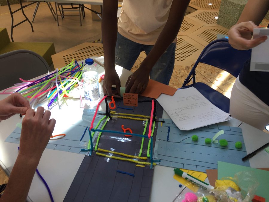 Participants from group Harmony building a prototype of an optimized intersection for cyclists and pedestrians using different colored cleaning pipes and construction paper