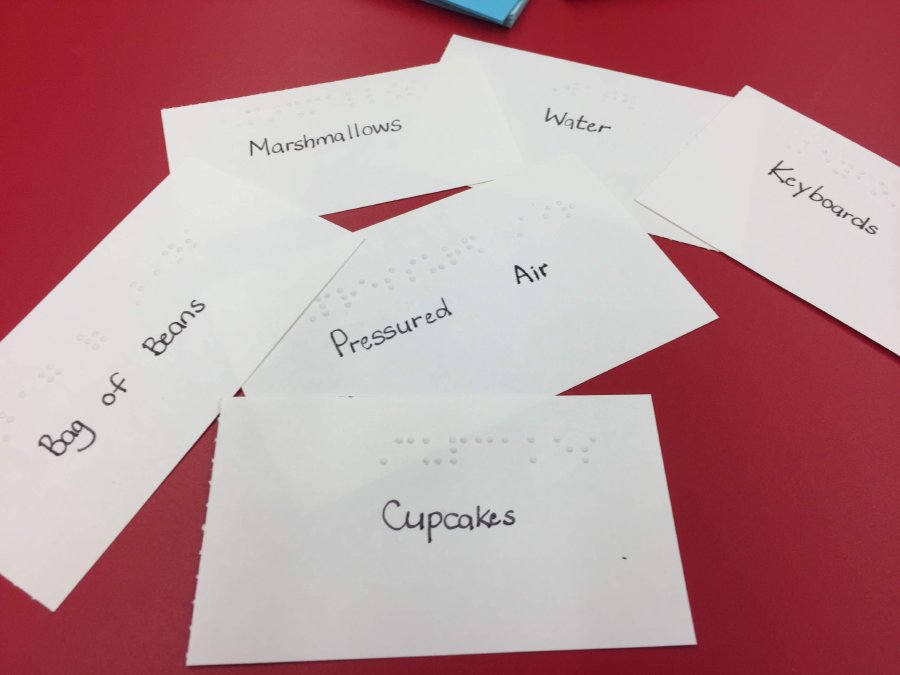Examples of items used for the warm up activity printed on braille cards. The cards pictured have names of items such as "bag of beans", "cupcakes", "pressured air", "marshmallows", "water" and "keyboards"