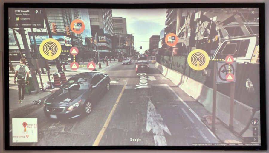 A screen showing a view of the street with colored circular images representing beacons warning pedestrians of construction impediments on the path